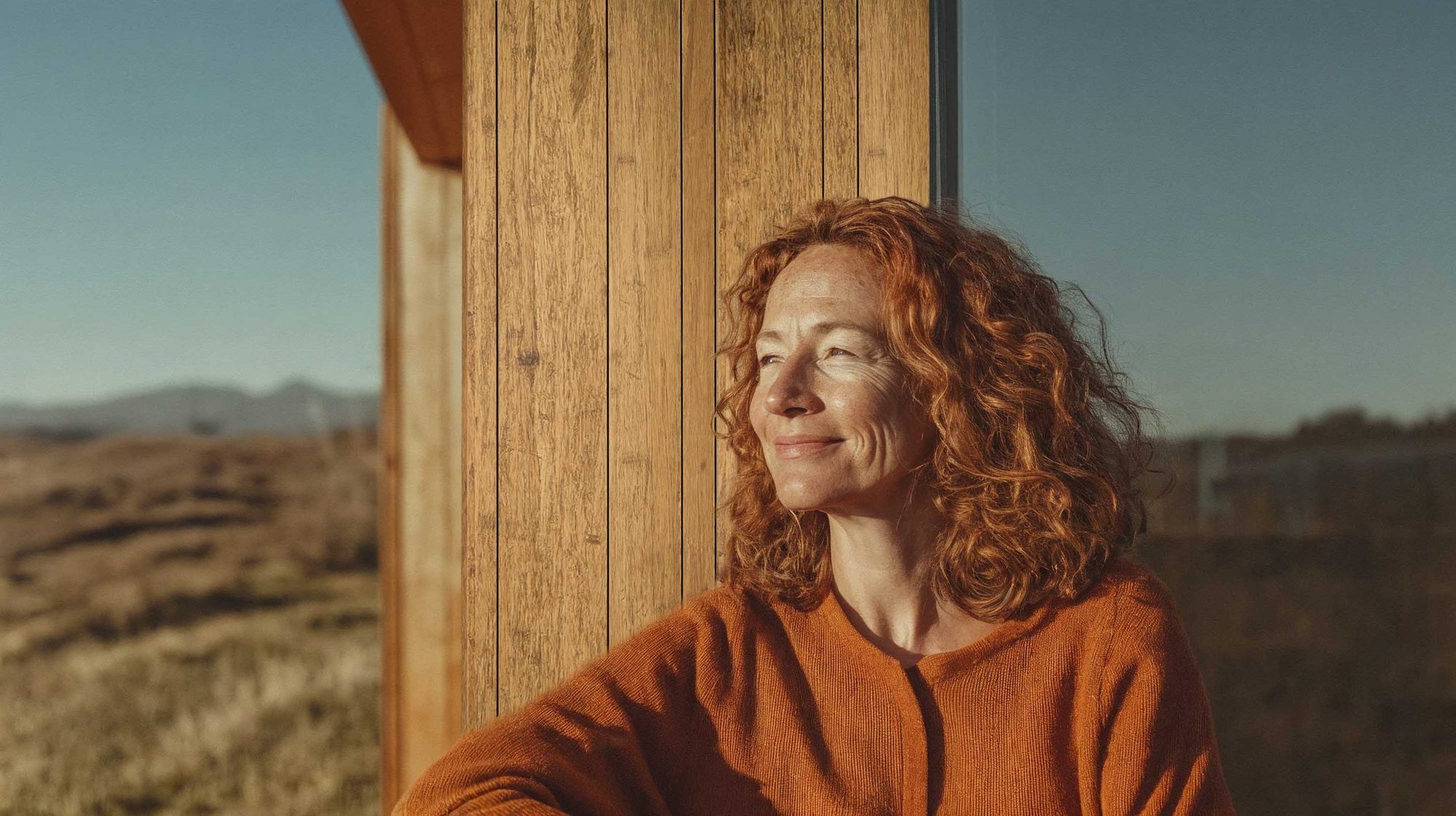 AMBOOO-Key-Visual: Frau im Abendlicht an einer Fassade aus Bambusprofilen